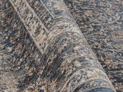 Nahaufnahme eines Frisé-Teppichs mit detailliertem Muster in Blau- und Beigetönen, seitliche Perspektive.