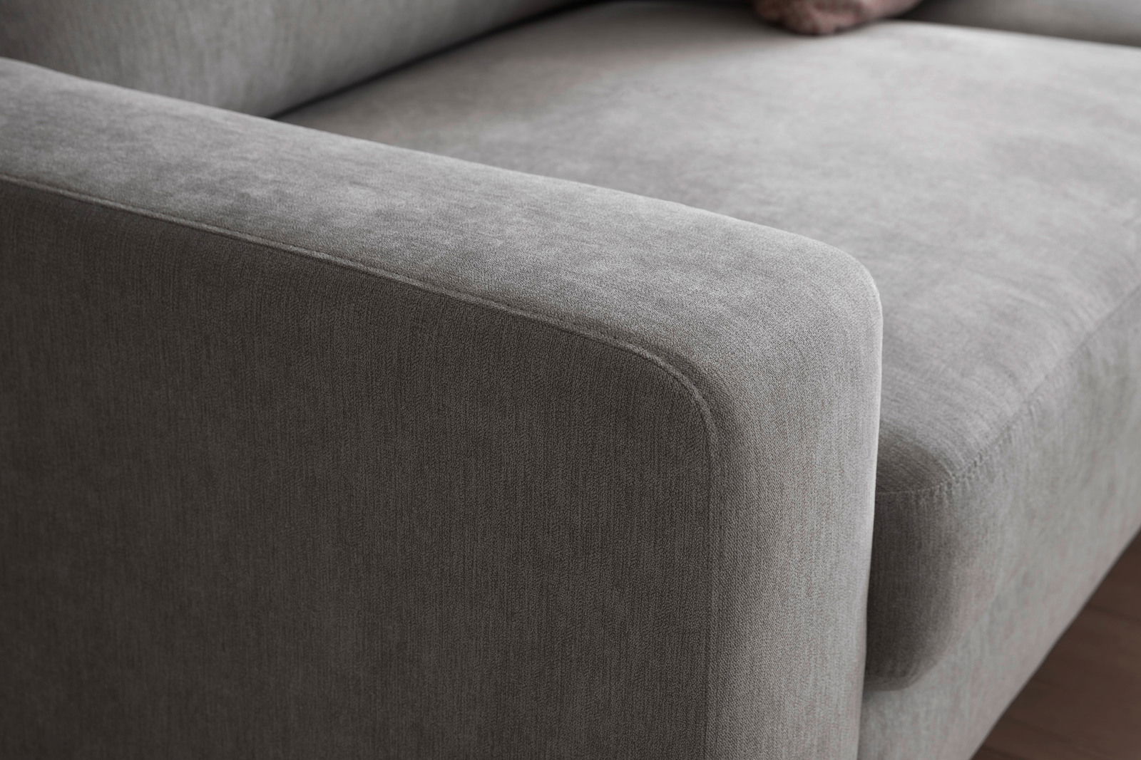 Nahaufnahme einer grauen Eckgarnitur mit weicher Polsterung, seitliche Perspektive