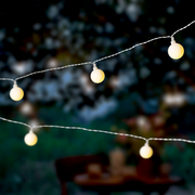 Nahaufnahme von leuchtenden Solar-Lichterketten in Kirschform bei Dämmerung im Freien