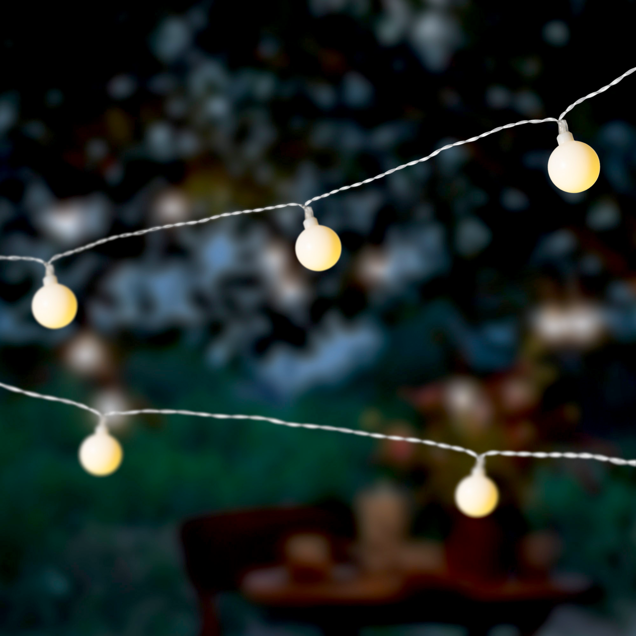 Nahaufnahme von leuchtenden Solar-Lichterketten in Kirschform bei Dämmerung im Freien