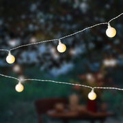 Nahaufnahme von leuchtenden Solar-Lichterketten in Kirschform bei Dämmerung im Freien