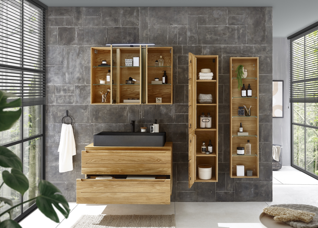 Moderner Waschtischunterschrank aus Holz mit schwarzem Waschbecken, umgeben von offenen und geschlossenen Regalen, in einem stilvollen Badezimmer mit grauen Fliesen. Frontalansicht.