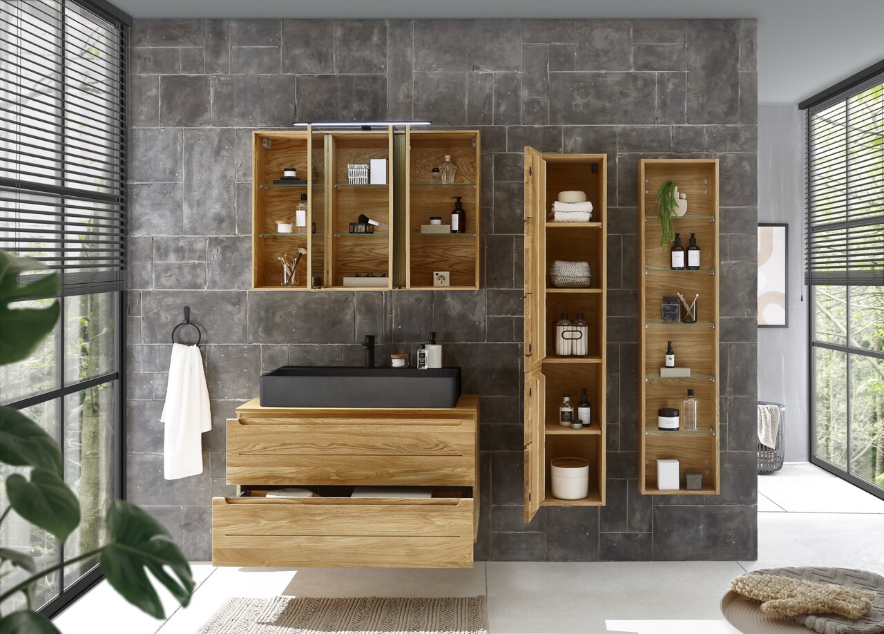 Moderner Waschtischunterschrank aus Holz mit schwarzem Waschbecken, umgeben von offenen und geschlossenen Regalen, in einem stilvollen Badezimmer mit grauen Fliesen. Frontalansicht.