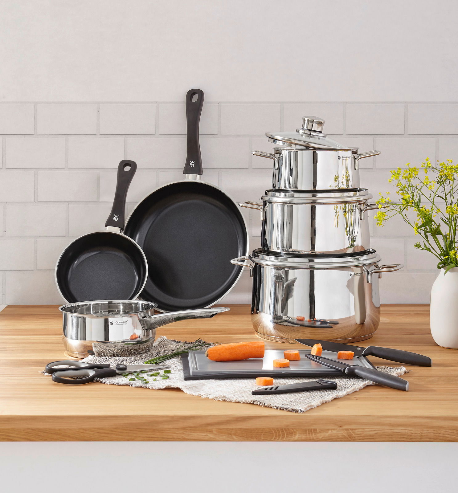 Kochtopf-Starter-Set 10-tlg. aus Edelstahl mit Töpfen, Pfannen und Küchenutensilien auf einer Holzarbeitsplatte, seitliche Perspektive.