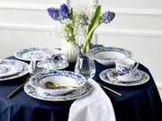 Gedeckter Tisch mit blau-weißem Porzellangeschirr im floralen Muster, goldfarbenem Besteck, Wassergläsern und Blumenvasen auf dunkelblauer Tischdecke, perspektivisch aus leicht erhöhter schräger Vorderansicht