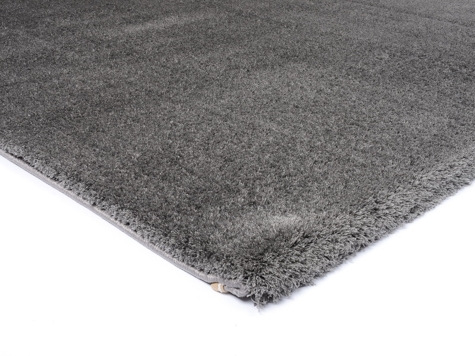 Grauer Hochflor-Teppich in Nahaufnahme, perspektivisch von der Seite fotografiert.