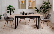 Moderner Esstisch mit Holzplatte und schwarzen Metallbeinen, umgeben von vier grauen Stühlen in einem stilvoll eingerichteten Raum mit Pflanzen und Wandkunst, frontal betrachtet.
