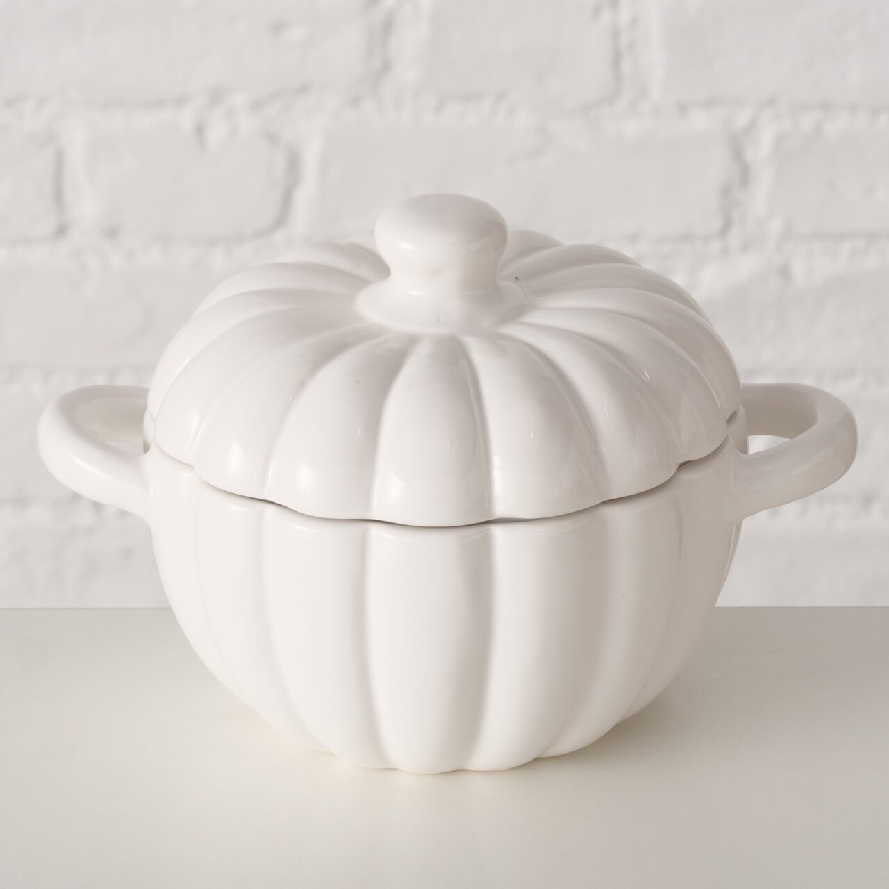 Weiße, kürbisförmige Auflaufform mit Deckel und zwei Henkeln, seitliche Perspektive.