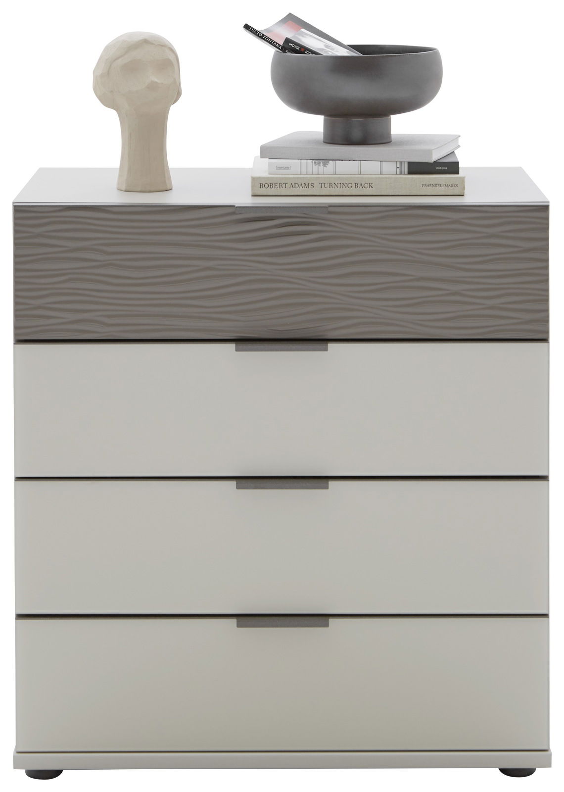 Schubkastenkommode mit vier Schubladen, obere Schublade mit wellenförmiger Struktur, dekoriert mit einer Skulptur, Büchern und einer Schale, Frontalansicht.