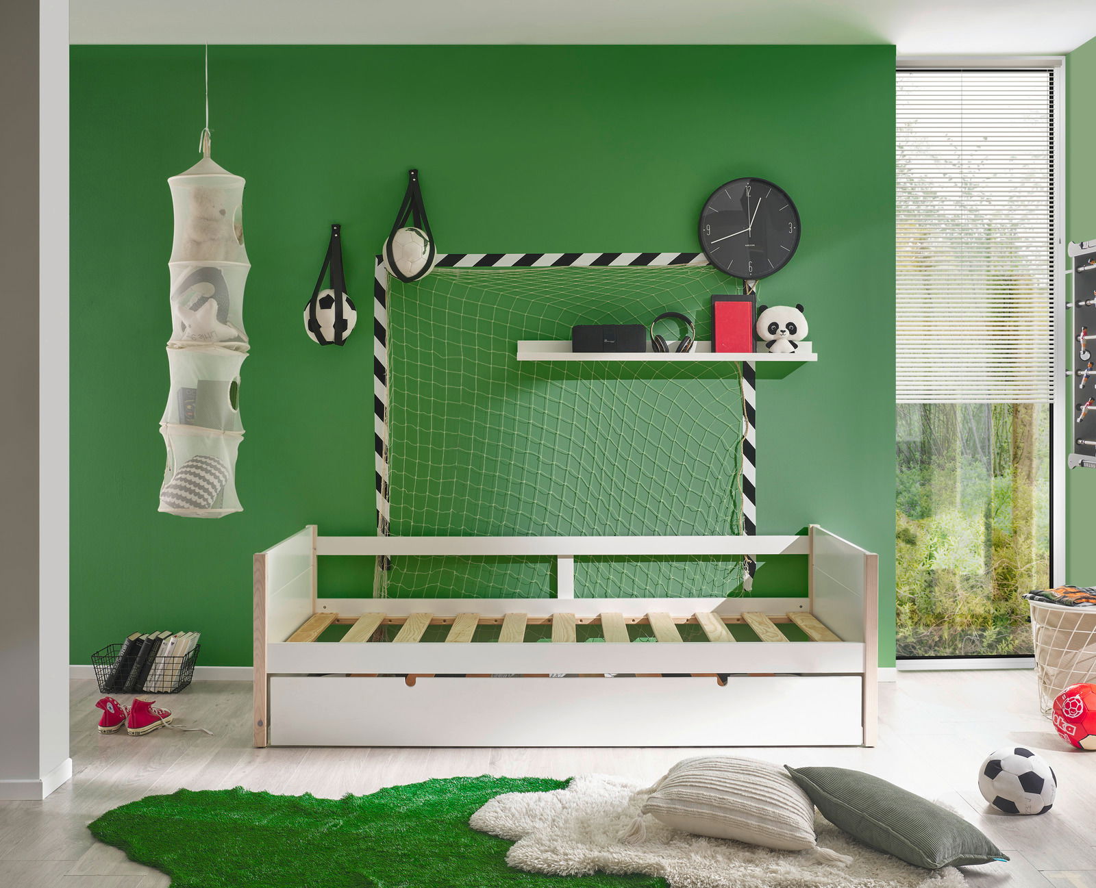 Jugendbett in einem sportlich dekorierten Zimmer mit grünem Fußballthema, seitliche Perspektive.