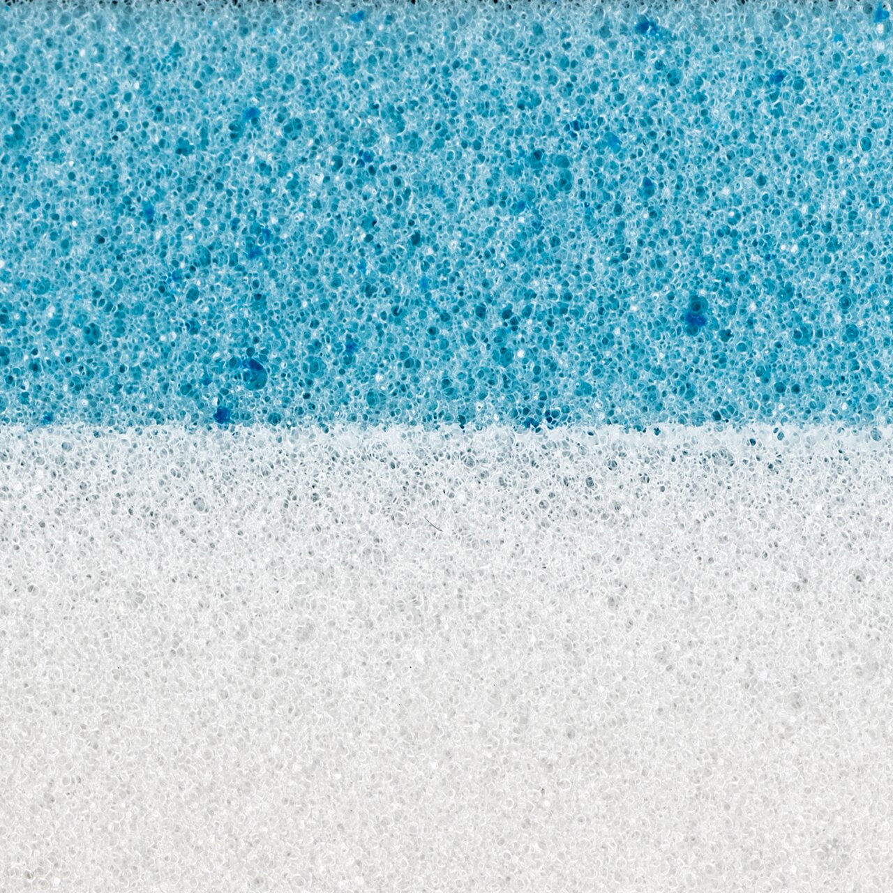 Nahaufnahme eines zweischichtigen Matratzentoppers mit einer weißen und einer blauen Schicht, seitliche Perspektive