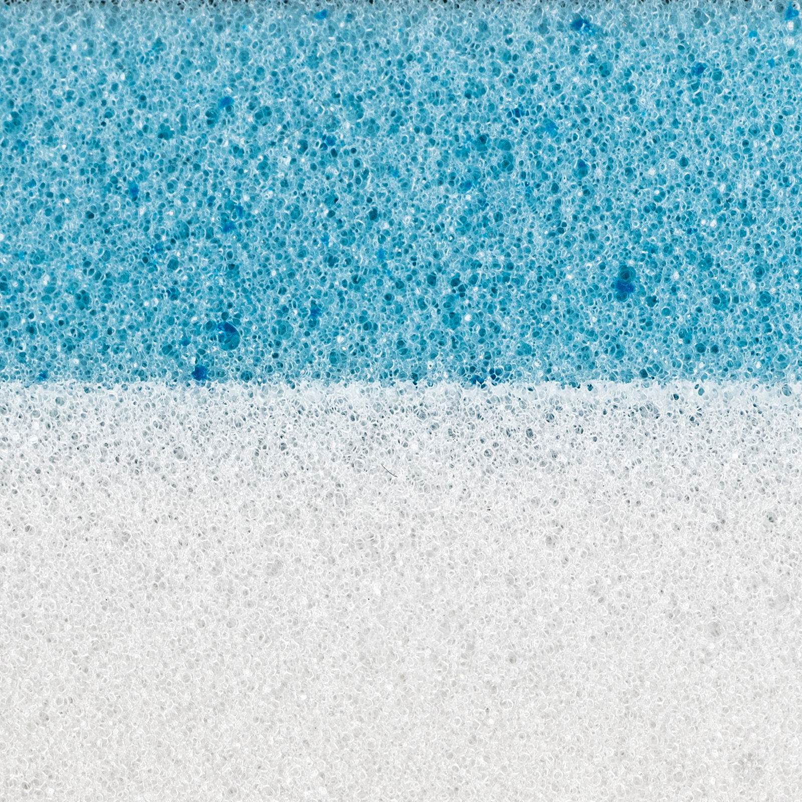 Nahaufnahme eines zweischichtigen Matratzentoppers mit einer weißen und einer blauen Schicht, seitliche Perspektive