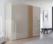 Moderner Schwebetürenschrank mit zwei Türen, eine mit Holzstreifen-Design, in einem hellen Raum mit Holzboden, seitliche Perspektive.