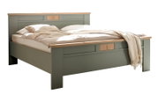 Modernes Doppelbett in Salbeigrün mit Holz-Akzenten an Kopf- und Fußteil, bezogen mit heller Bettwäsche und Decke, freigestellt auf weißem Hintergrund, Perspektive: schräg von vorne (3/4-Ansicht)