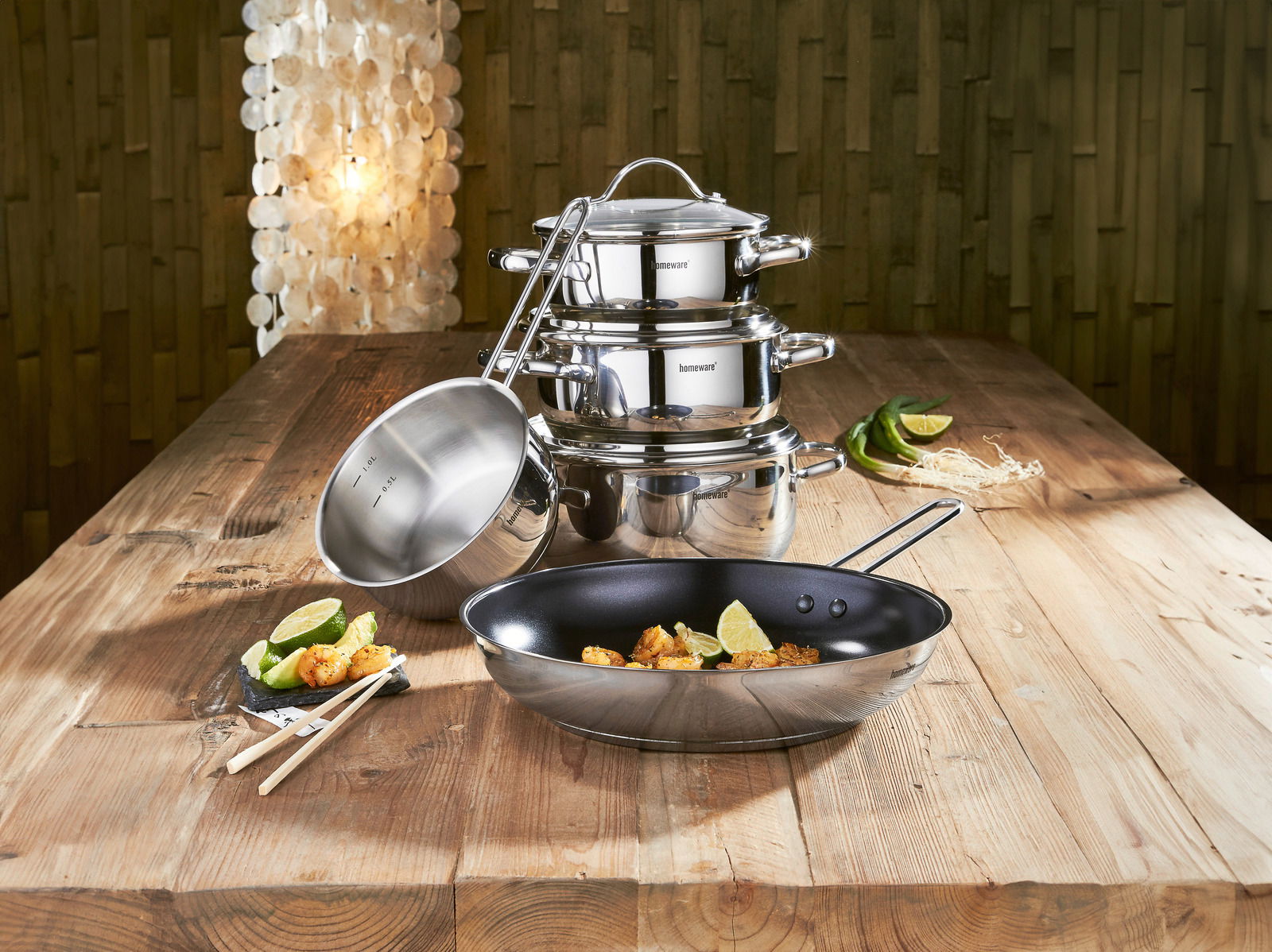 Homeware Kochtopfset 5-teilig Kochtopfset 5-teilig aus Edelstahl, bestehend aus mehreren Töpfen und einer Pfanne, auf einem Holztisch arrangiert. Perspektive von vorne.