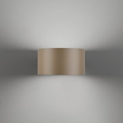 De wandlamp PURE Clipse, gezien van voren, die een zacht licht op de muur werpt.