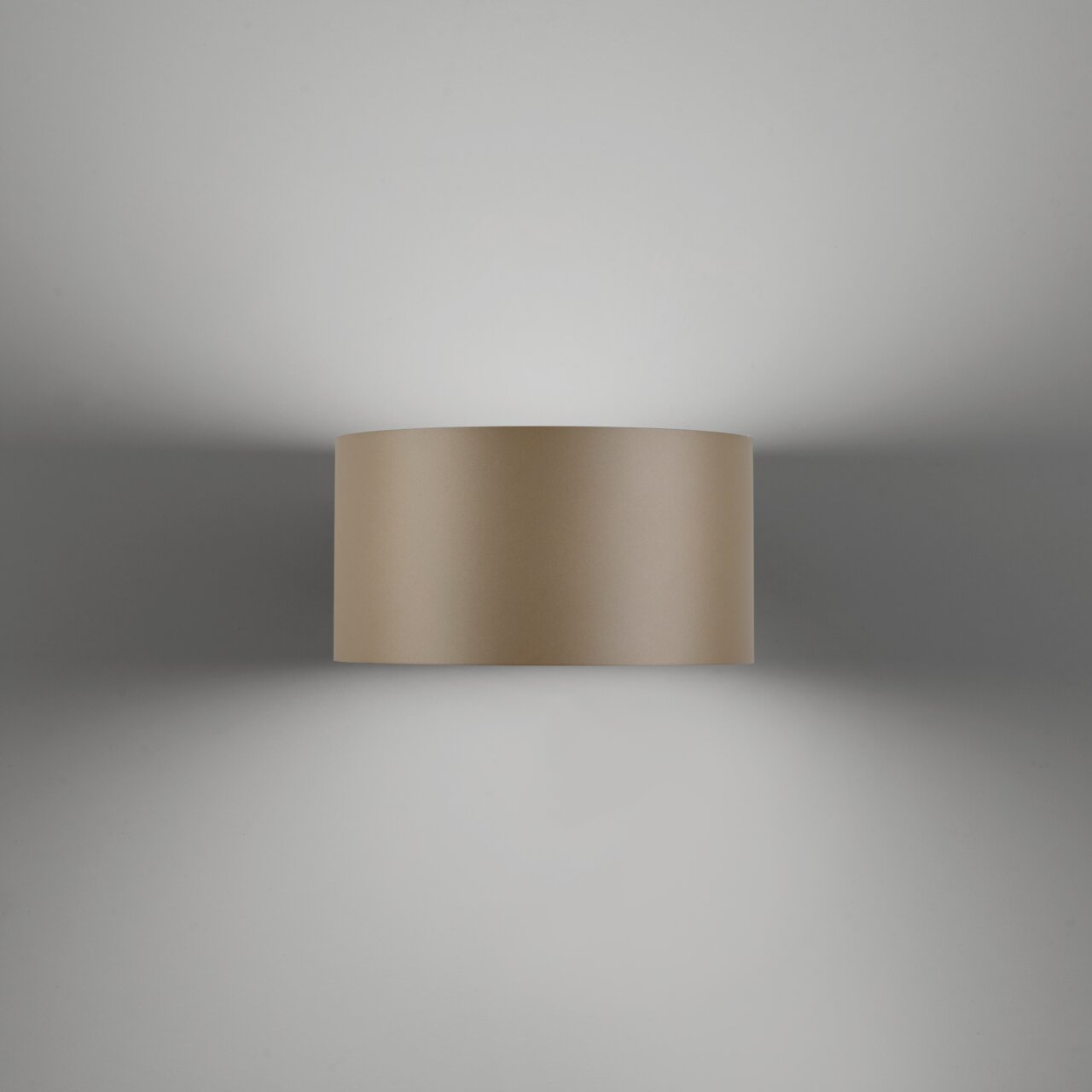 De wandlamp PURE Clipse, gezien van voren, die een zacht licht op de muur werpt.