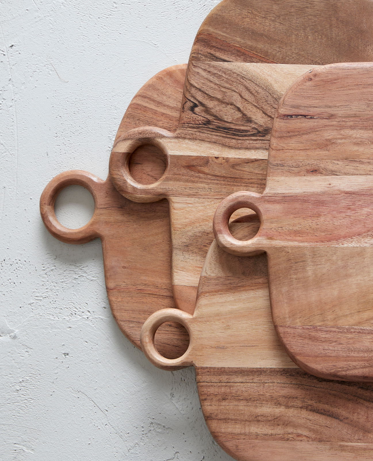 Drei übereinanderliegende Schneidebretter aus Holz mit runden Griffen, von oben betrachtet.