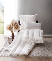 Ein gemütliches Bett-Set mit veganen Kissen und Decke in einem modernen Raum, seitliche Perspektive.