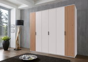 Sechstüriger Drehtürenschrank in modernem Design mit weißen Türen und Holzpaneelen, seitliche Perspektive.