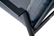 Close-up van een Comfort Plus stapelstoel met een zwart metalen frame en een grijze stoffen bekleding, gezien vanaf de zijkant