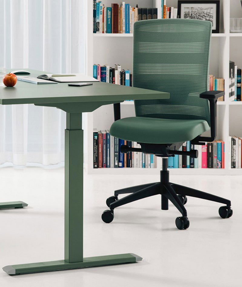 Sitness Bürostuhl AIRWORK Grüner Bürostuhl mit Netzrückenlehne und schwarzen Armlehnen, seitliche Perspektive, neben einem grünen Schreibtisch in einem modernen Büro mit Bücherregal im Hintergrund.