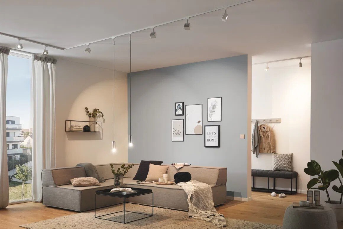 Modernes Wohnzimmer mit grauem L-förmigem Ecksofa, schwarzem Couchtisch und Wandbildern, aufgenommen aus frontaler Weitwinkelperspektive.