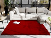 Roter Fellteppich im Wohnzimmer vor einem beigen Sofa, von oben betrachtet.