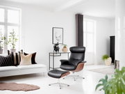 Moderner Relaxsessel mit Hocker in einem hellen Wohnzimmer, seitliche Perspektive
