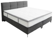 Boxspringbett in seitlicher Perspektive mit grauem Kopfteil und weißer Matratze
