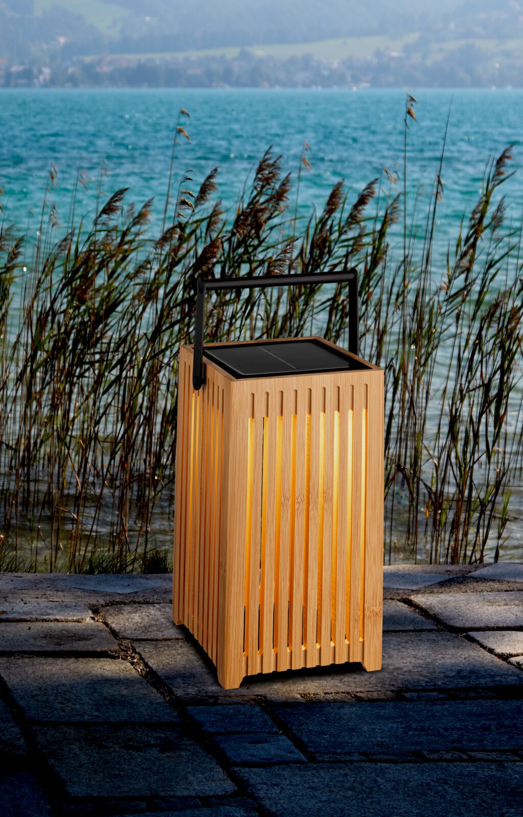 Holz-Solarleuchte mit Griff, leuchtend auf einer Terrasse am Seeufer, seitliche Perspektive