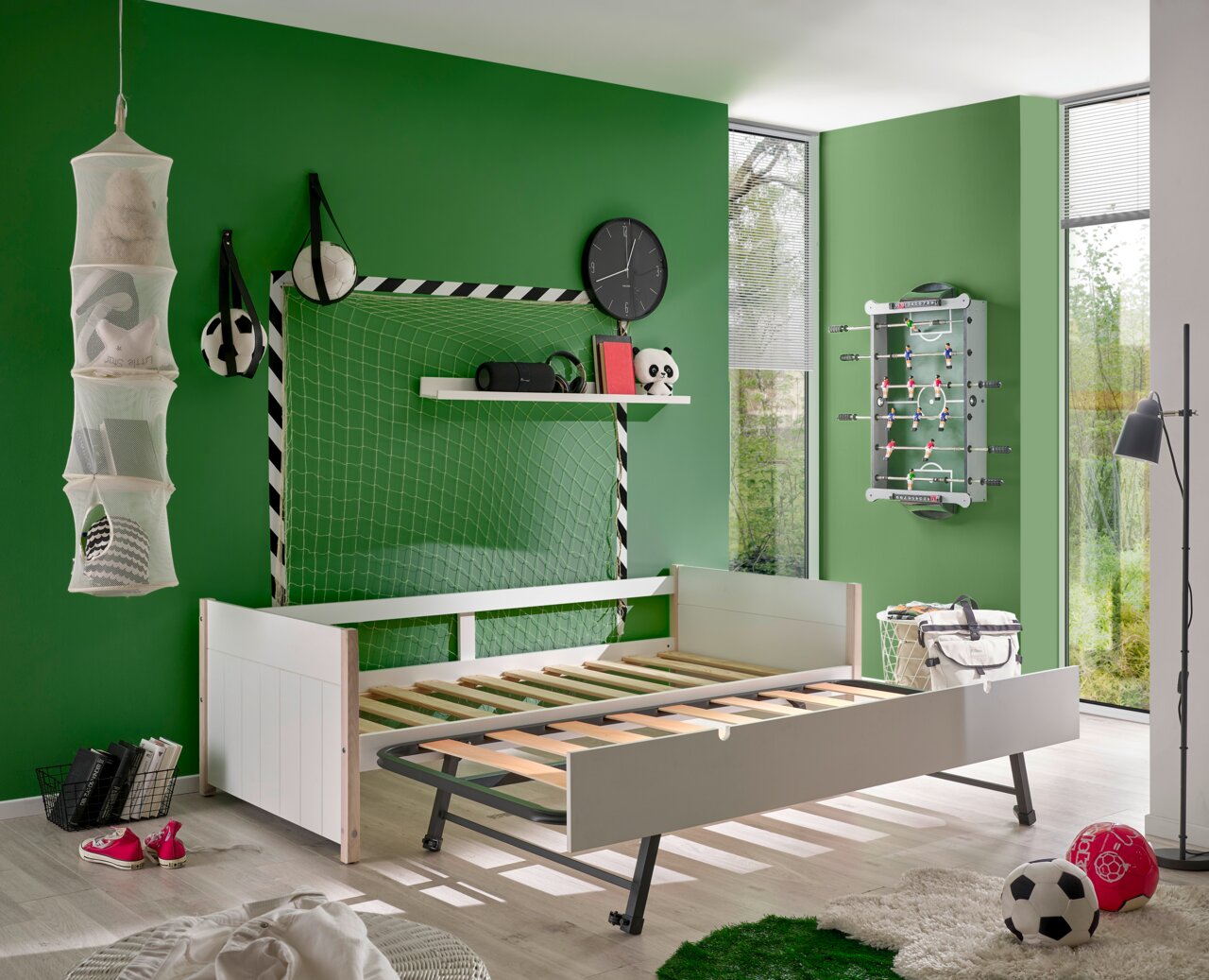 Jugendbett in einem sportlich dekorierten Zimmer mit Fußballthema, seitliche Perspektive