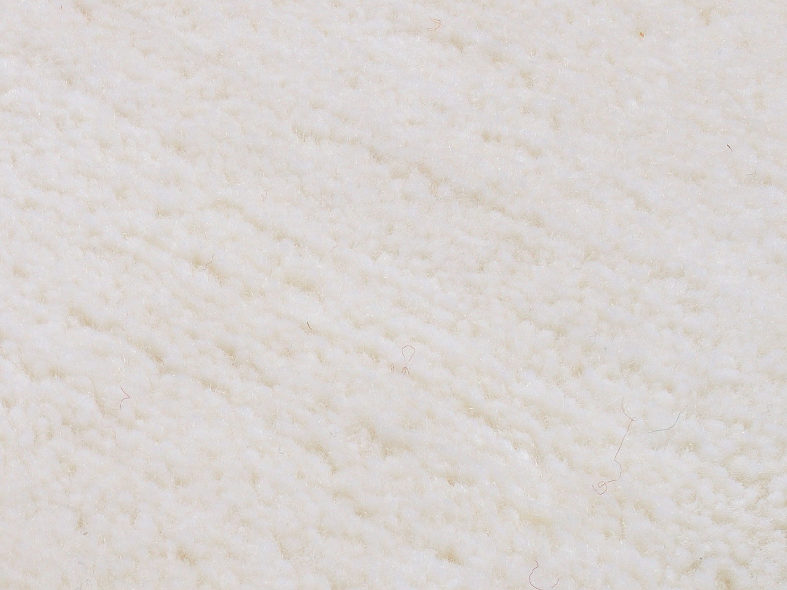 Nahaufnahme eines weißen Wollteppichs mit weicher, flauschiger Textur.