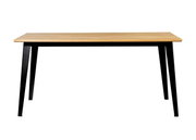 Moderne eettafel met houten blad en zwarte metalen poten, van voren gefotografeerd.