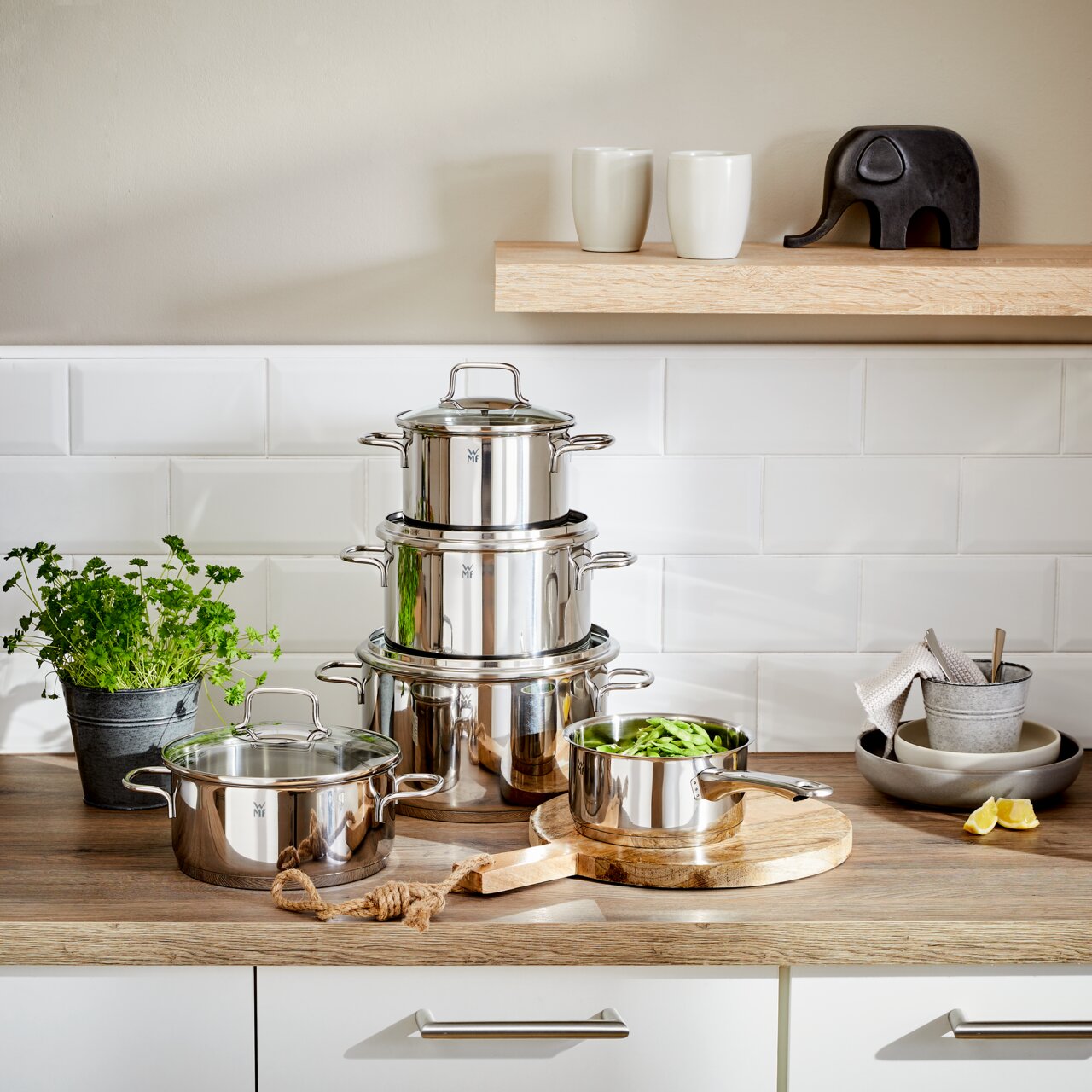 Topfset Astoria 5-tlg. aus Edelstahl, gestapelt auf einer Küchenarbeitsplatte, mit einem Topf voller grüner Bohnen im Vordergrund. Perspektive: Frontalansicht.