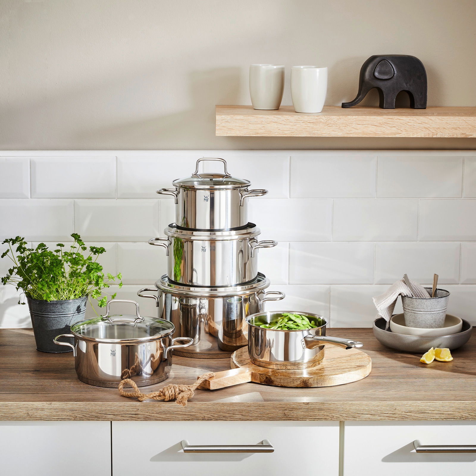 Topfset Astoria 5-tlg. aus Edelstahl, gestapelt auf einer Küchenarbeitsplatte, mit einem Topf voller grüner Bohnen im Vordergrund. Perspektive: Frontalansicht.