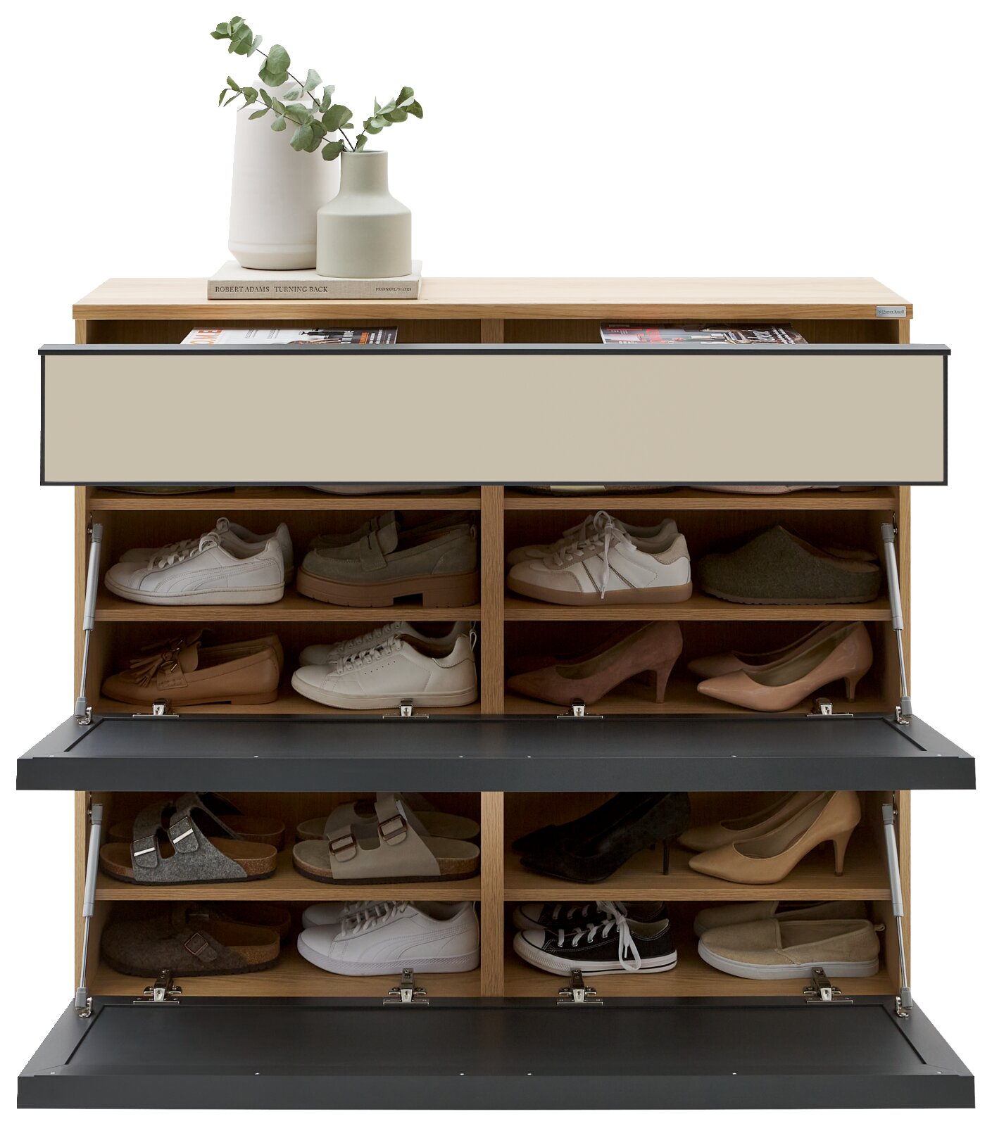 Frontalansicht eines modernen Schuhschranks aus hellem Holz mit drei nach vorn geöffneten Klappen in Schwarz und beigen Fronten, oben mit Vasen und Büchern dekoriert