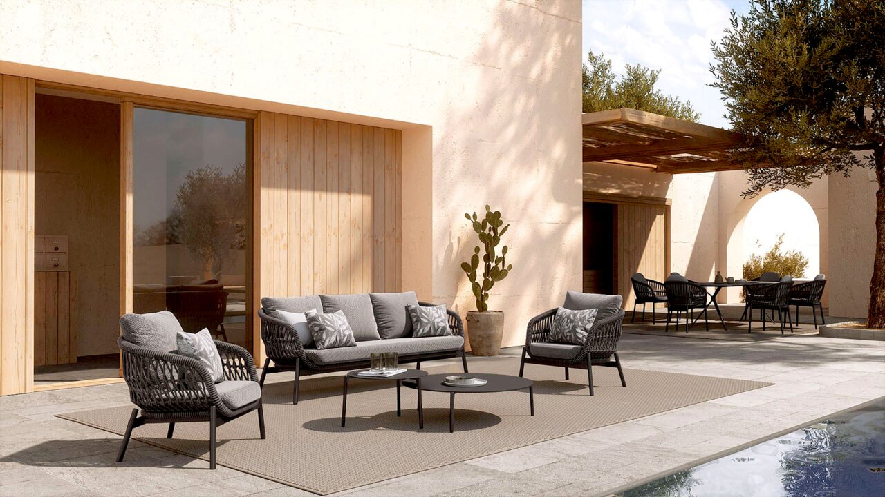 Moderne Loungegarnitur und Beistelltische auf einer Terrasse mit Blick auf den Pool, umgeben von mediterraner Architektur.