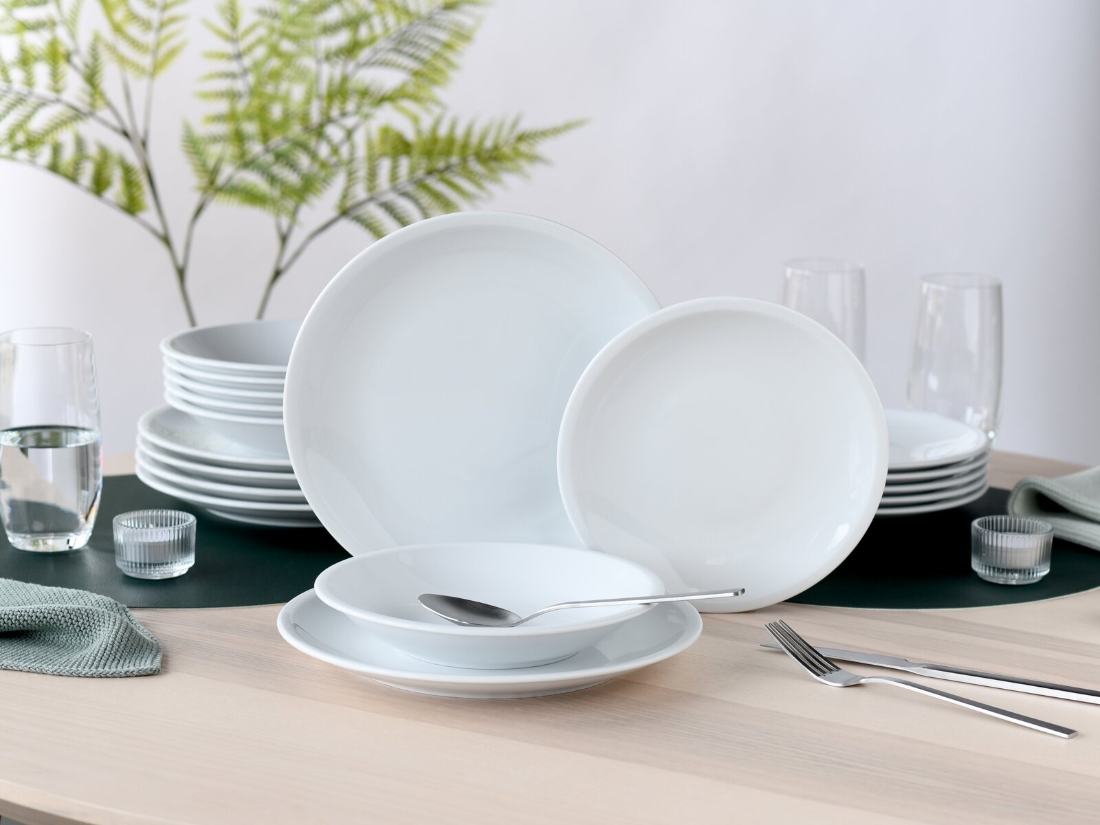 creaTable Tellerset 18-tlg MILANO Weißes, minimalistisches Porzellan-Geschirrset mit großen und kleinen Tellern sowie Schale auf gedecktem Holztisch, fotografiert in leichter Frontansicht auf Augenhöhe mit leichtem Seitenwinkel.