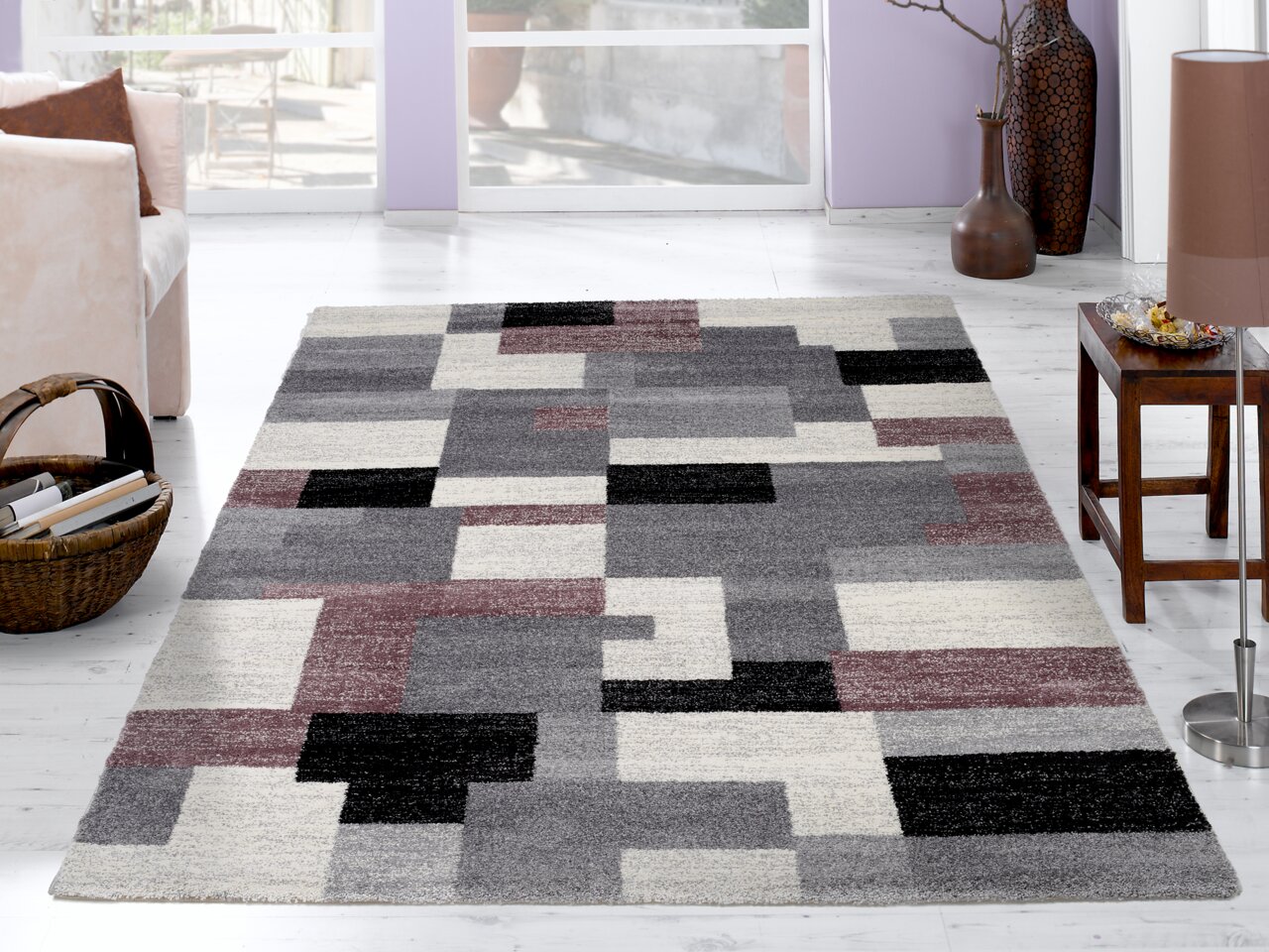 Moderner Frisé-Teppich mit geometrischem Muster in Grau-, Schwarz- und Rottönen, in einem hellen Wohnzimmer mit Blick auf den Teppich von oben.