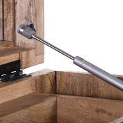 Nahaufnahme eines Scharniers und einer Gasdruckfeder an einer Schubkastenkommode aus Holz, seitliche Perspektive.