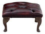 Elegante poef met donkerrode, gestoffeerde lederen bekleding en decoratieve knopen, gezien van voren.