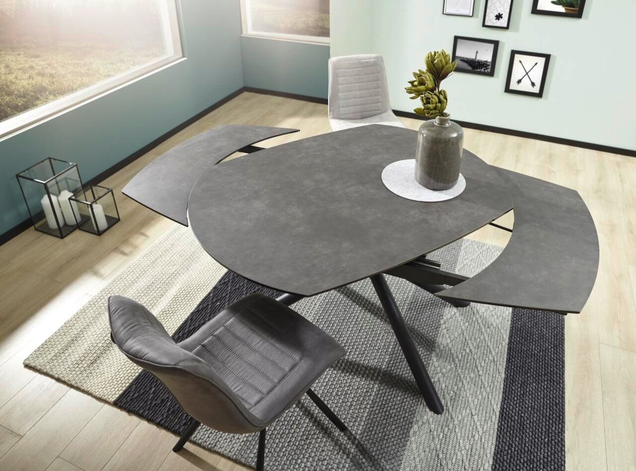 Moderner Esstisch Novel BINZ in dunkler Steinoptik mit ausziehbarer Tischplatte, fotografiert aus der Vogelperspektive, umgeben von stilvollen Stühlen und Dekoration.