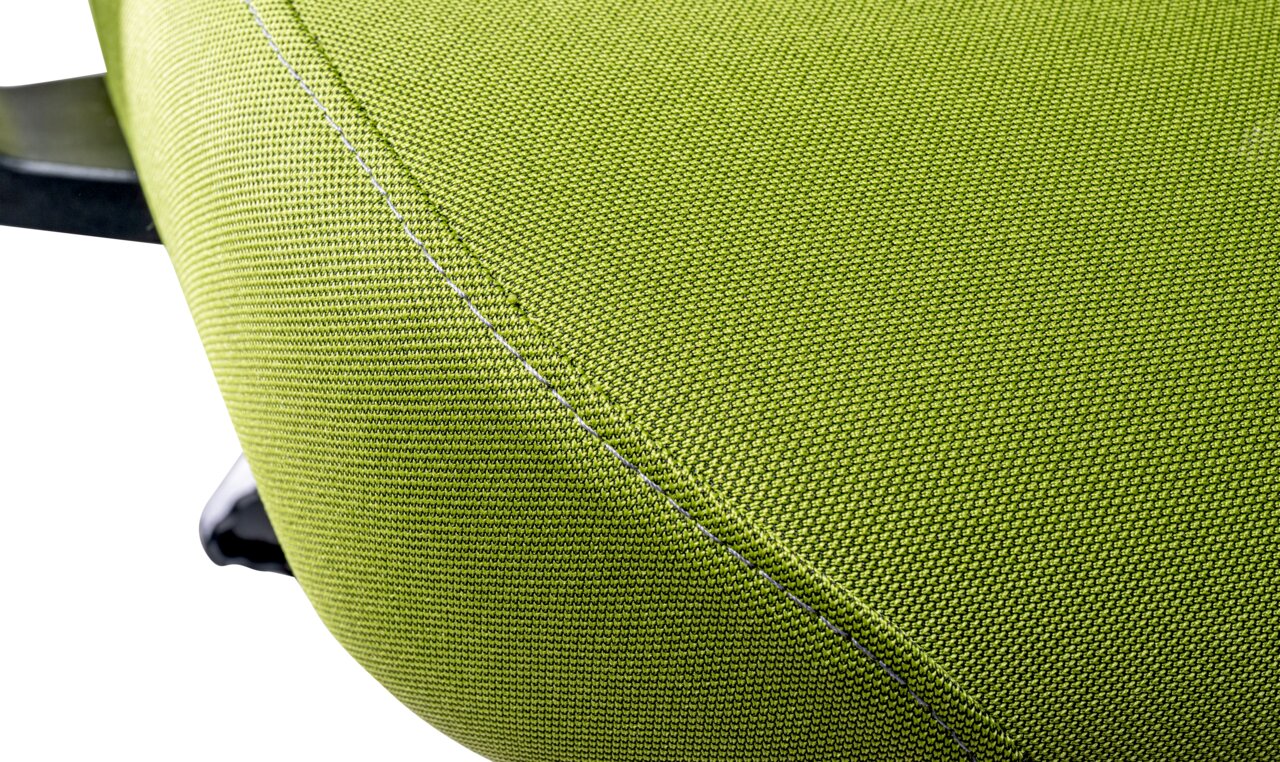Nahaufnahme eines grünen Stoffbezugs eines Drehstuhls, seitliche Perspektive
