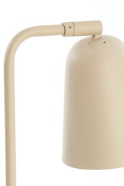 Close-up vanuit vooraanzicht van een beige metalen lamp met gebogen frame en cilindervormige kap