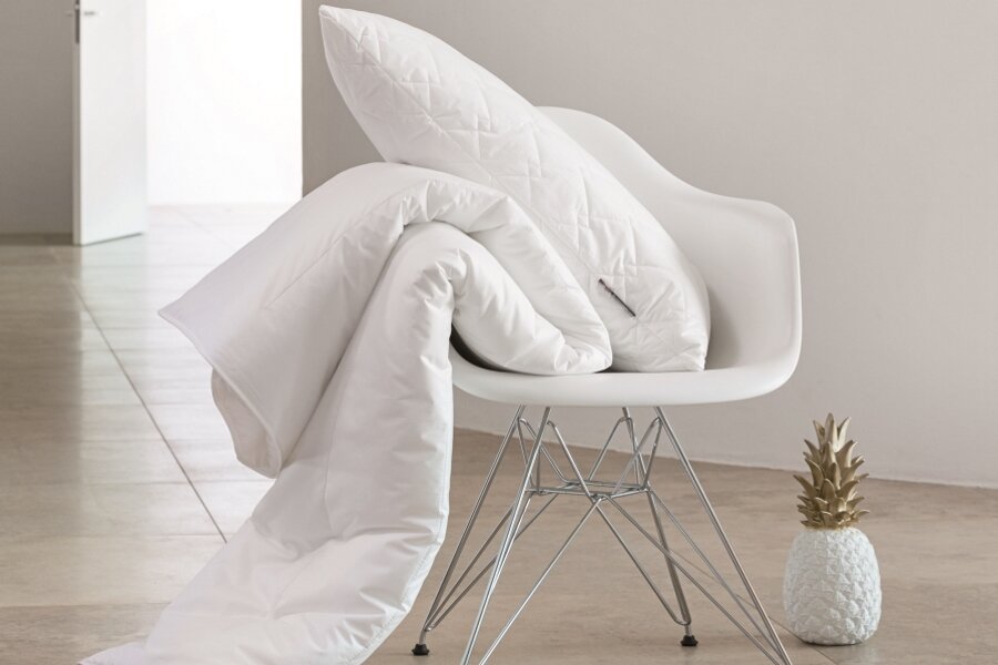 Ganzjahresbettdecke 155x220cm auf einem modernen Stuhl drapiert, seitliche Perspektive