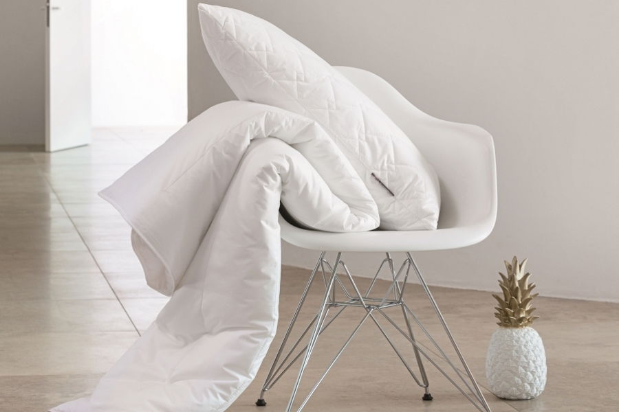 Ganzjahresbettdecke 155x220cm auf einem modernen Stuhl drapiert, seitliche Perspektive