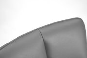 Close-up van de bovenhoek van een grijze leren fauteuil, gezien van bovenaf.