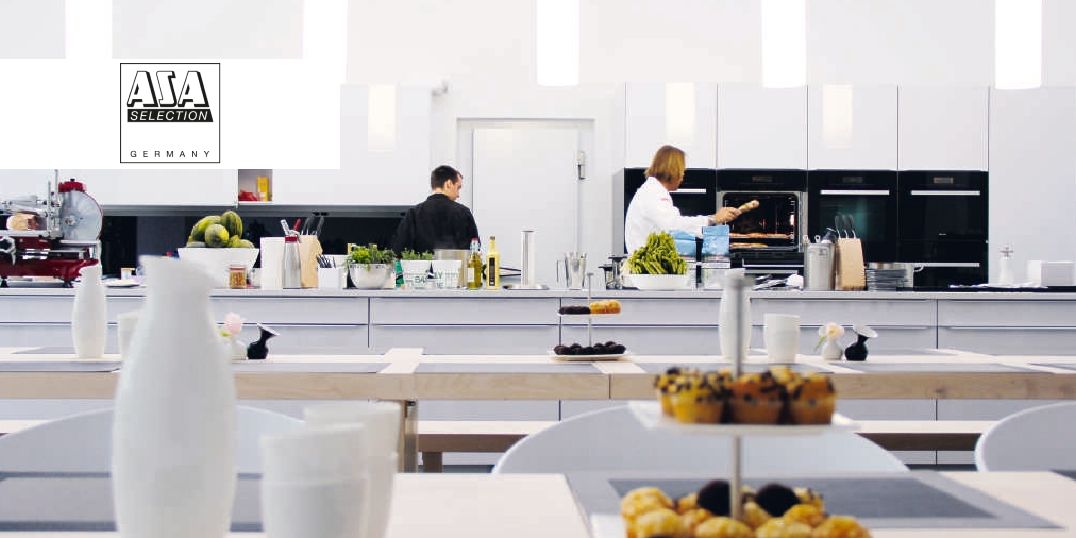 Een moderne keuken met koks die gerechten bereiden, met elegante tafels, verse ingrediënten en stijlvolle apparatuur.