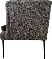 Gepolsterter Polsterstuhl mit grau-schwarz meliertem Bouclé-Bezug und schwarzen Metallbeinen, Seitenansicht (leicht von hinten)